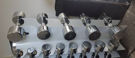 A wall-mounted rack with multiple dumbbells of varying weights.
