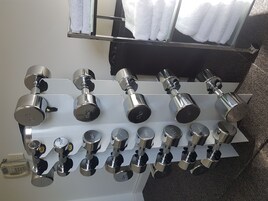 Estante de pared con mancuernas de diferentes pesos.