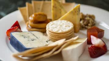 A plate with various cheeses, crackers, and fruits.