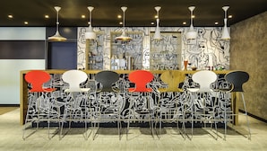 Eine Bar mit einer einzigartigen Schwarz-Weiß-Muralmalerei, modernen Barhocker und Pendelleuchten.