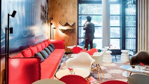 Ein modernes Interieur mit einem roten Sofa, weißen Stühlen und einem großen Fenster.