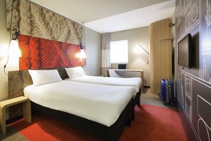 Een hotelkamer met twee bedden, een bureau, een televisie en een koffer.