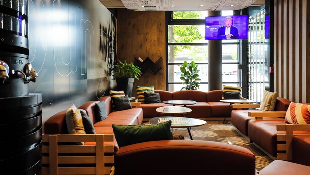 Ein stilvoller Lounge-Bereich mit Ledersofas, einem Couchtisch und einem Fernsehbildschirm.