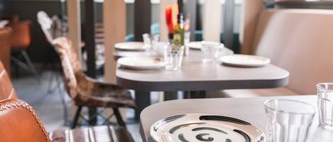 Un comedor con una mesa lista para dos personas, que incluye un plato con diseño en espiral, un vaso y una botella de agua.