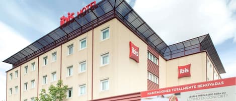 A hotel building with a red roof and multiple windows.