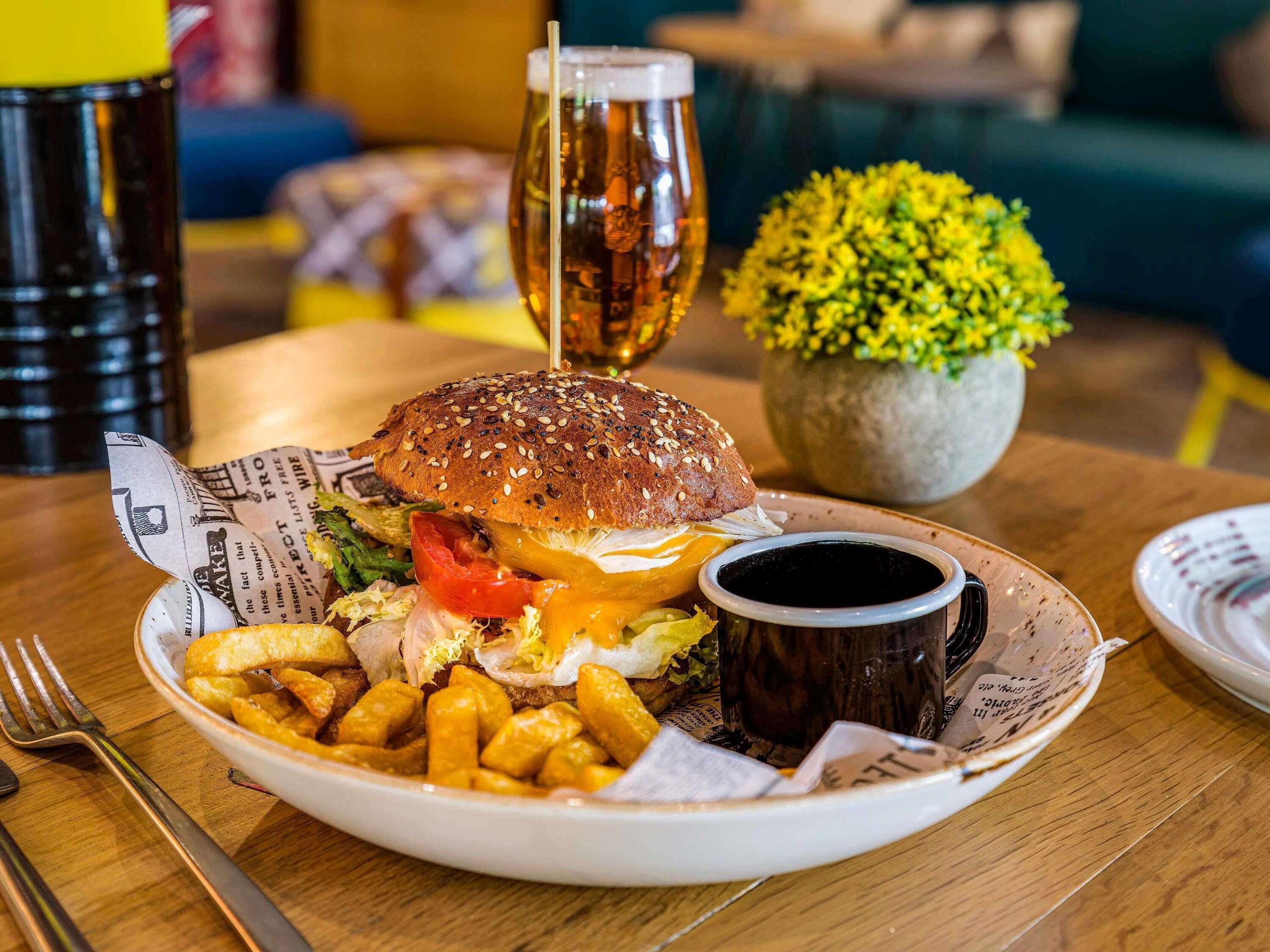 A meal with a burger, fries, and a drink on a wooden table.