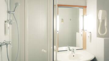 A bathroom with a glass-enclosed shower, a sink, and a mirror.