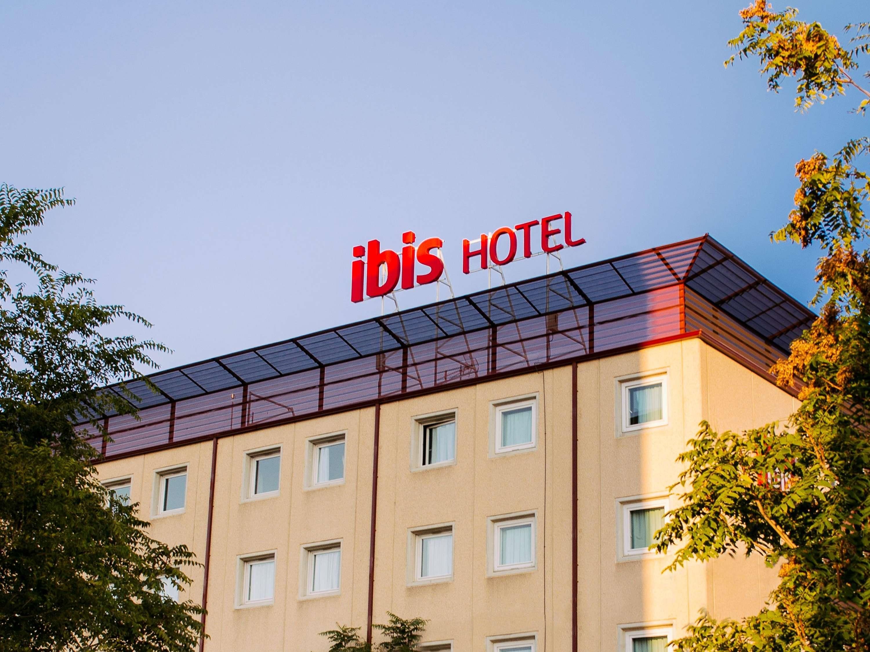 Un edificio de hotel con cielo despejado y un cartel en el techo que dice 'ibis HOTEL'.
