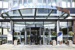 Experience the Novotel Edinburgh Centre's sleek entrance with a revolving door and clear glass facade offering unobstructed views of the interior.