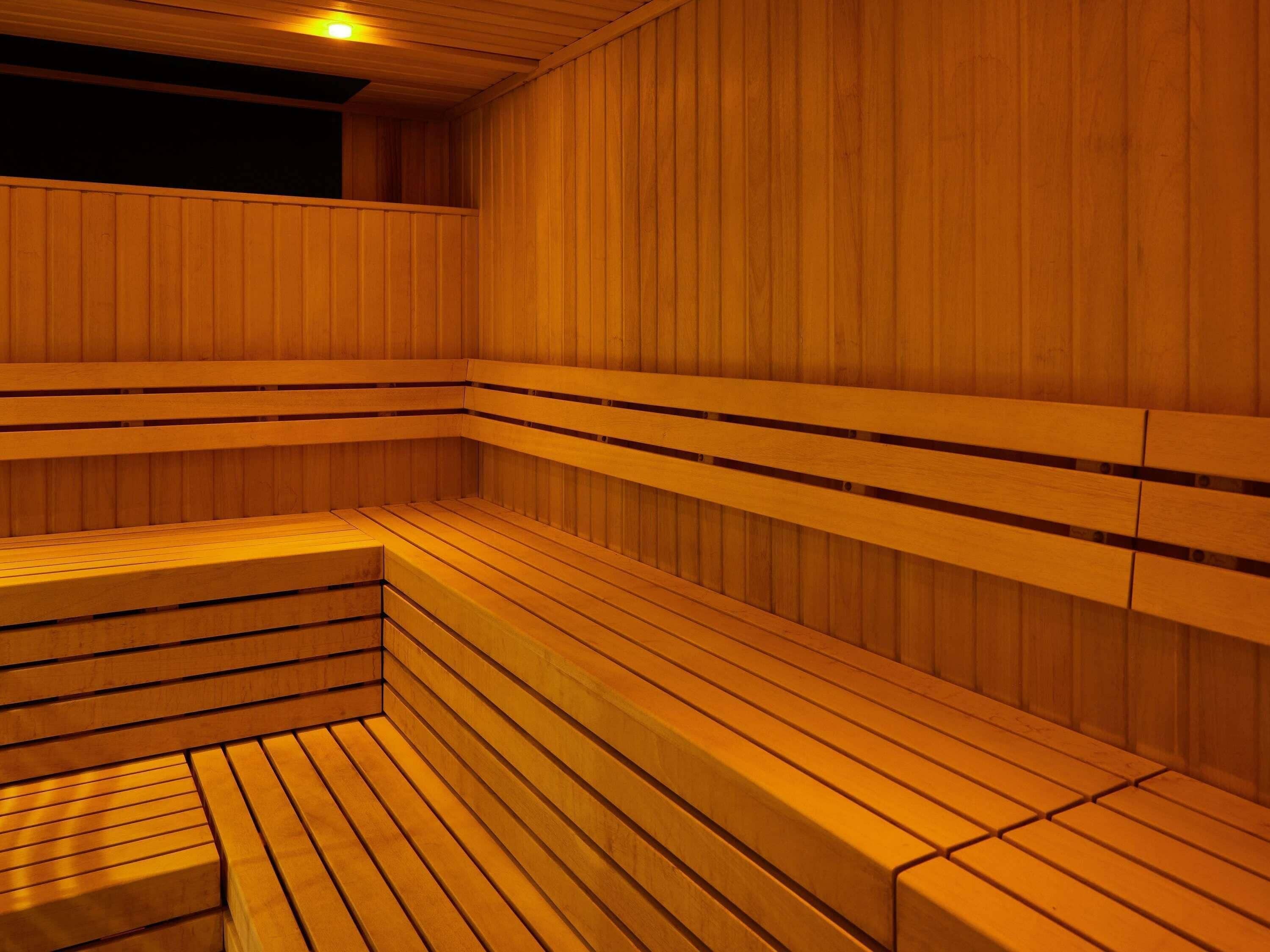 A sauna with wooden benches and walls, a sloped ceiling, and a small window.