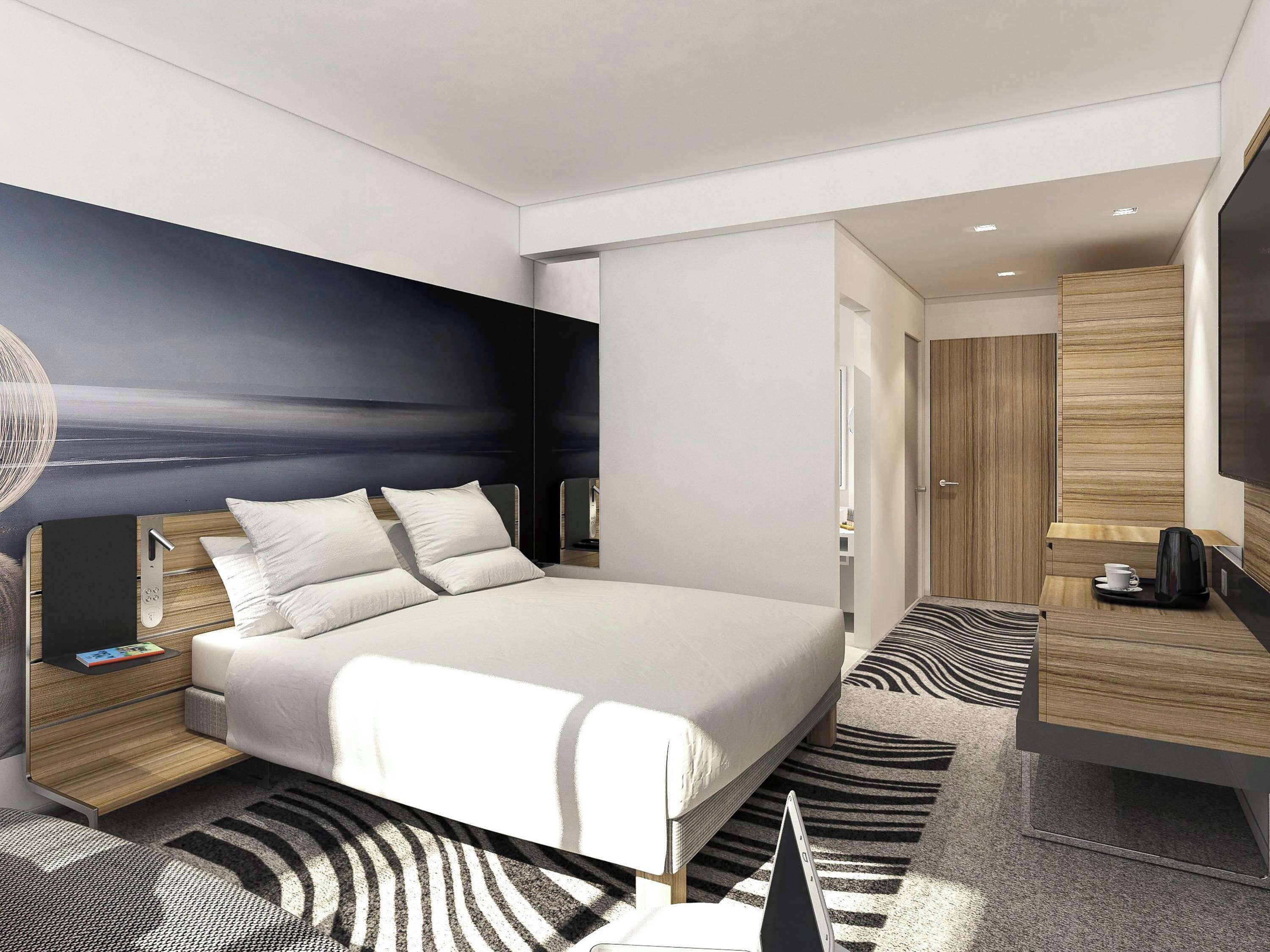 Een moderne hotelkamer met een groot bed, een bureau en een flatscreen televisie.