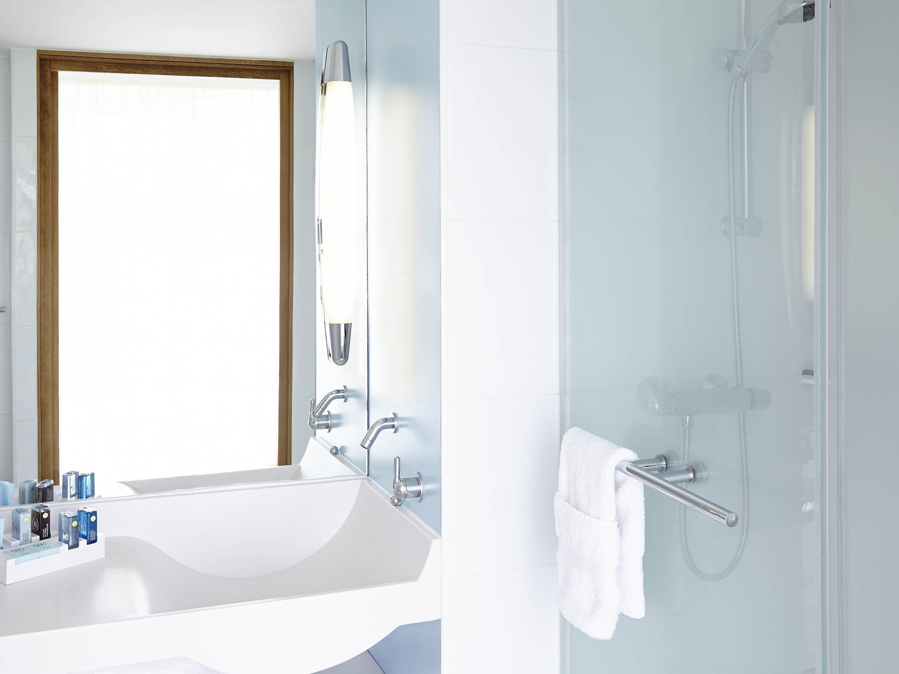 A bathroom with a white sink, mirror, and shower.