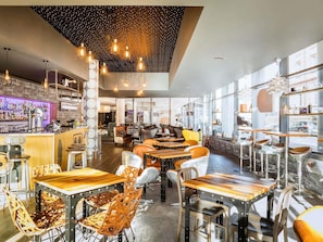 Ein modernes Restaurant mit freiliegenden Backsteinwänden, Holztischen und hängenden Leuchten.