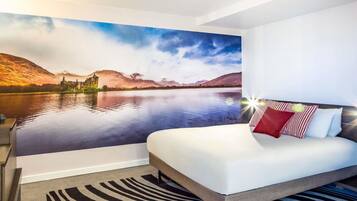 A bedroom with a bed, a zebra-patterned rug, and a scenic mural of a lake and mountains.