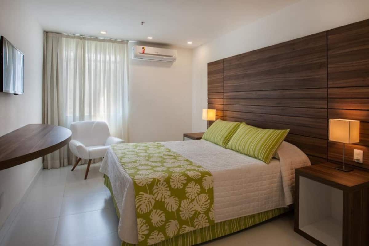 Une chambre d’hôtel comprenant un lit, un bureau, une chaise et une table de chevet avec des lampes.