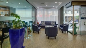 A modern lobby with a blue sofa, two armchairs, a coffee table, and a large potted plant. - Rio Design Copacabana Hotel (Rio de Janeiro)