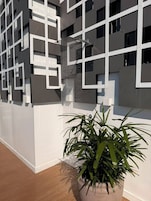 En moderne bygning med geometriske mønstre og en potteplante i forgrunden.