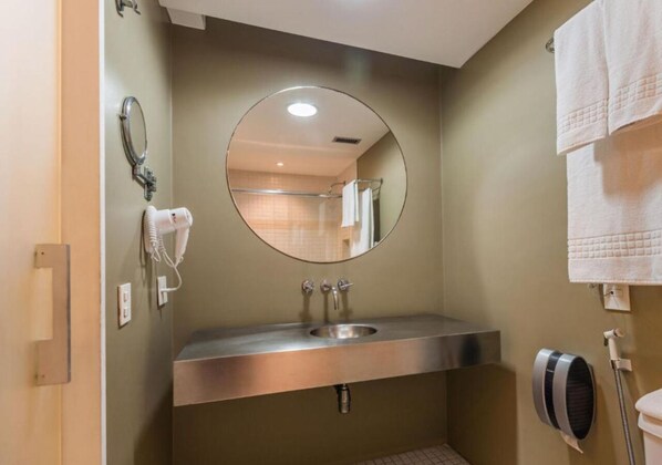 Un baño con lavamanos, espejo, toallero y secador de pelo.