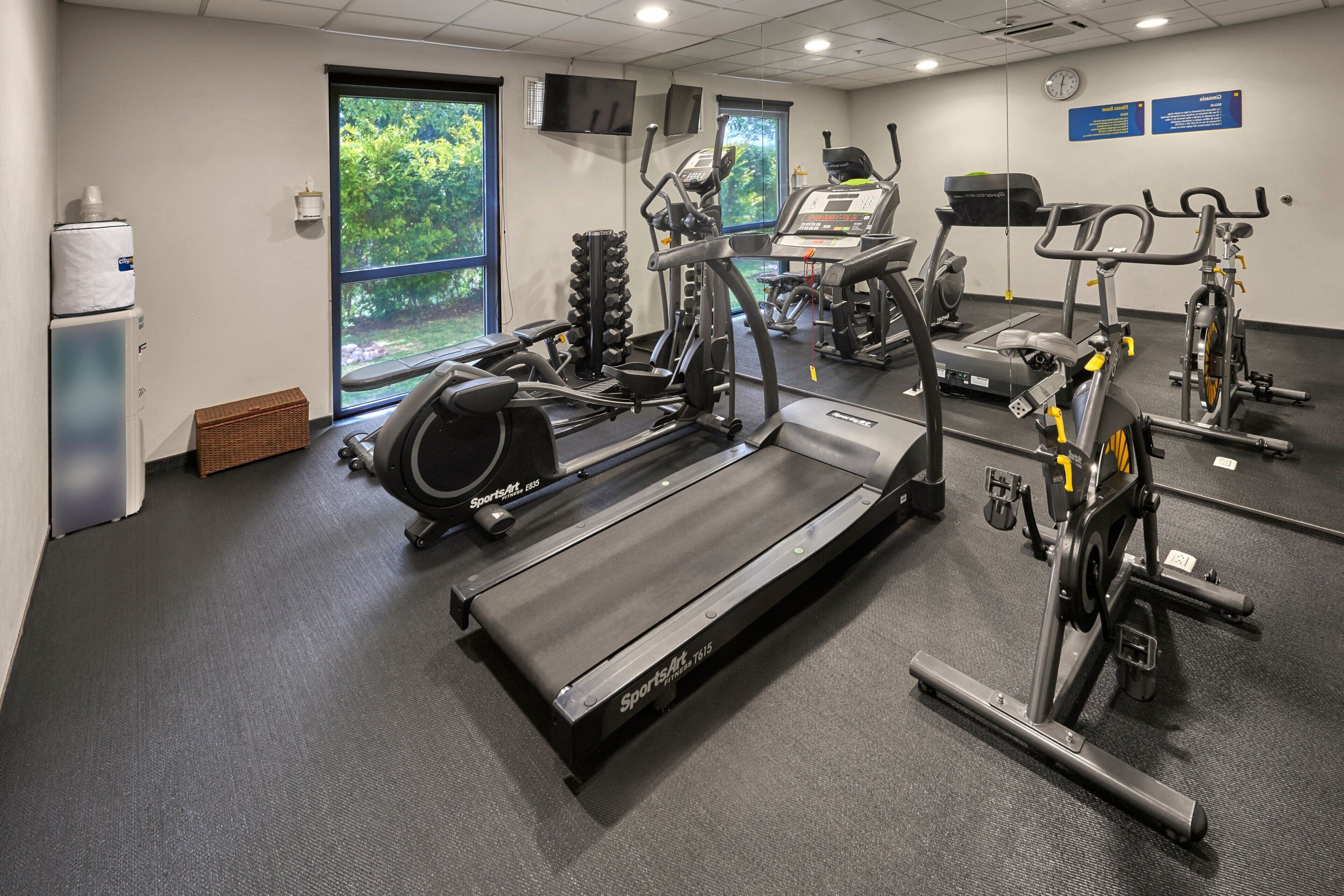 A gym with cardio machines, weight stations, and a treadmill.