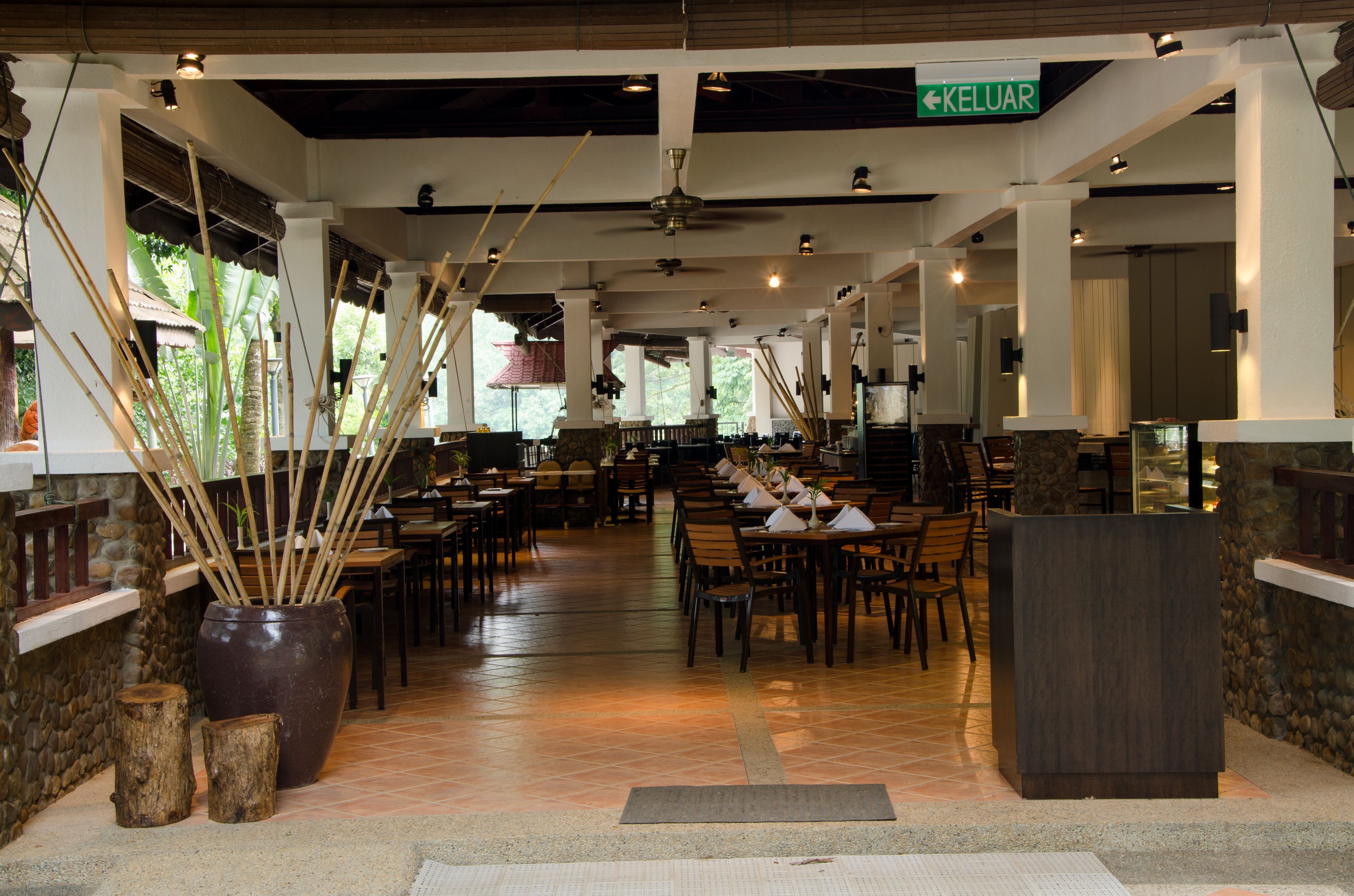 Un restaurant spacieux avec de hauts plafonds, des poutres en bois et une colonne centrale.