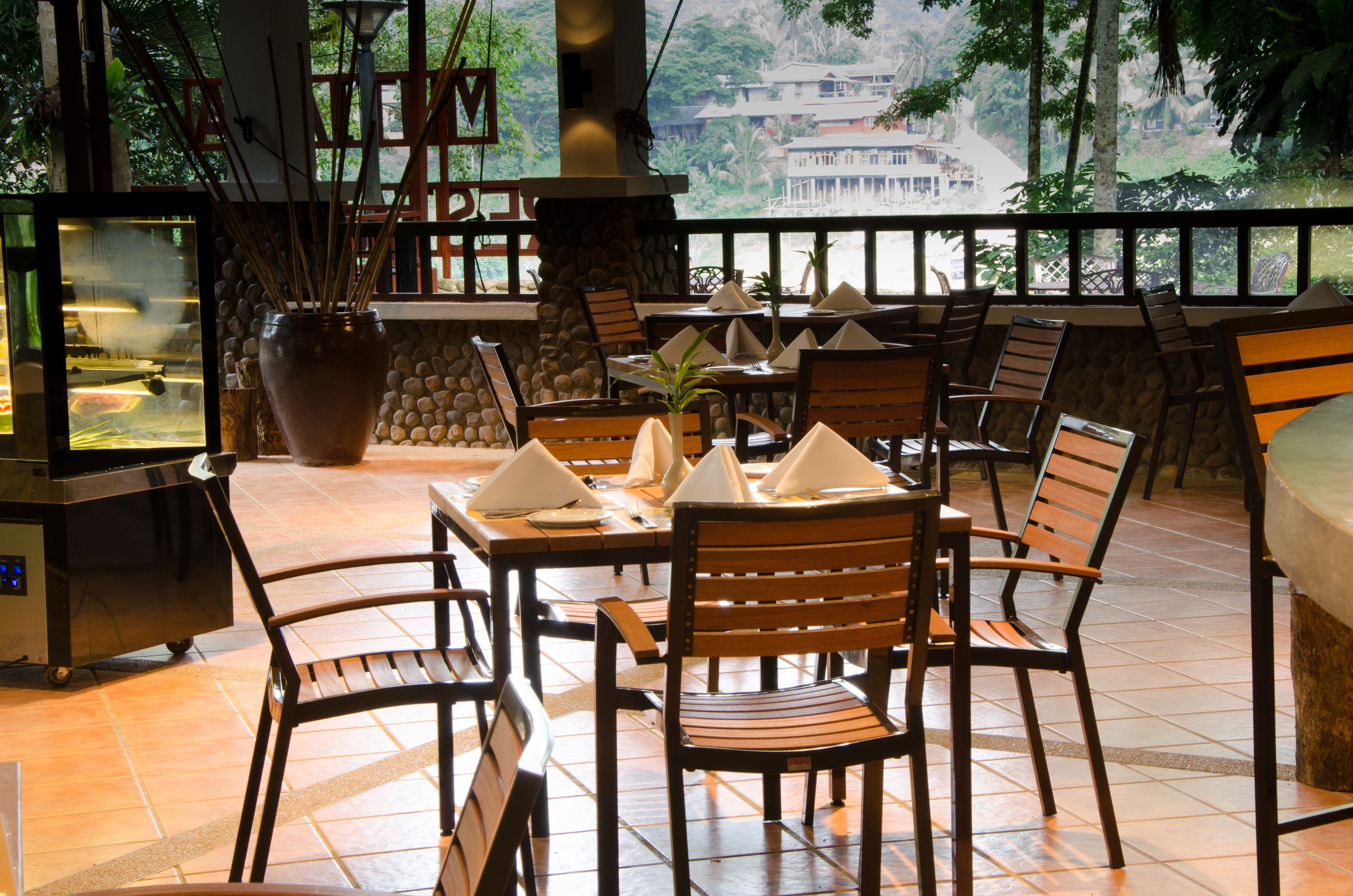 Un restaurant doté d’une terrasse, de murs en pierre et offrant une vue sur une montagne et un bâtiment.