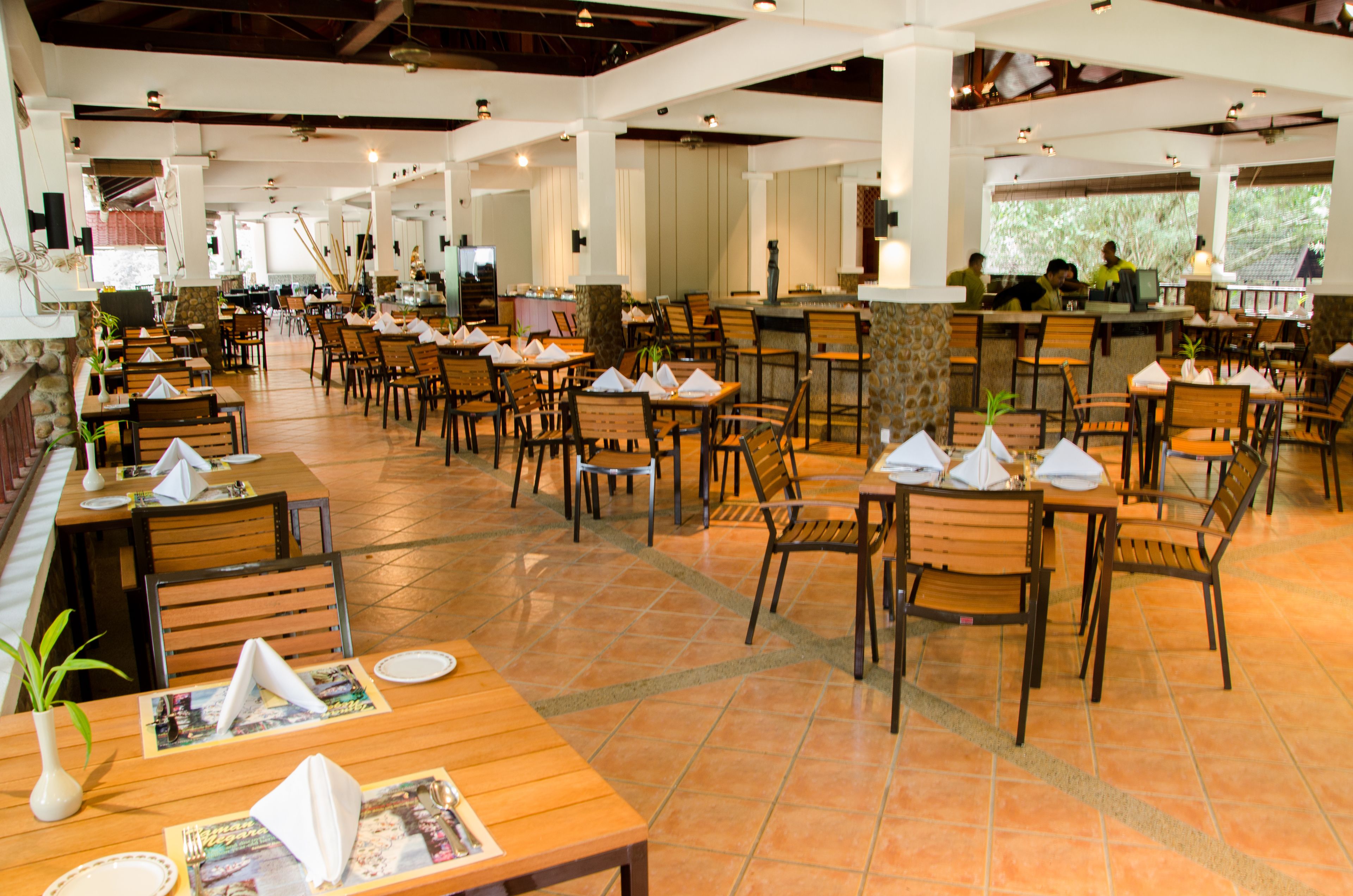 Un restaurant spacieux doté de nombreuses tables et chaises, d’un bar et offrant une vue sur l’extérieur.