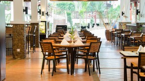 Un restaurante con un pilar de piedra, sillas y mesas de madera preparadas para comer.