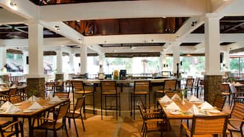 A spacious restaurant with multiple dining areas, a central bar, and a view of the outdoors.
