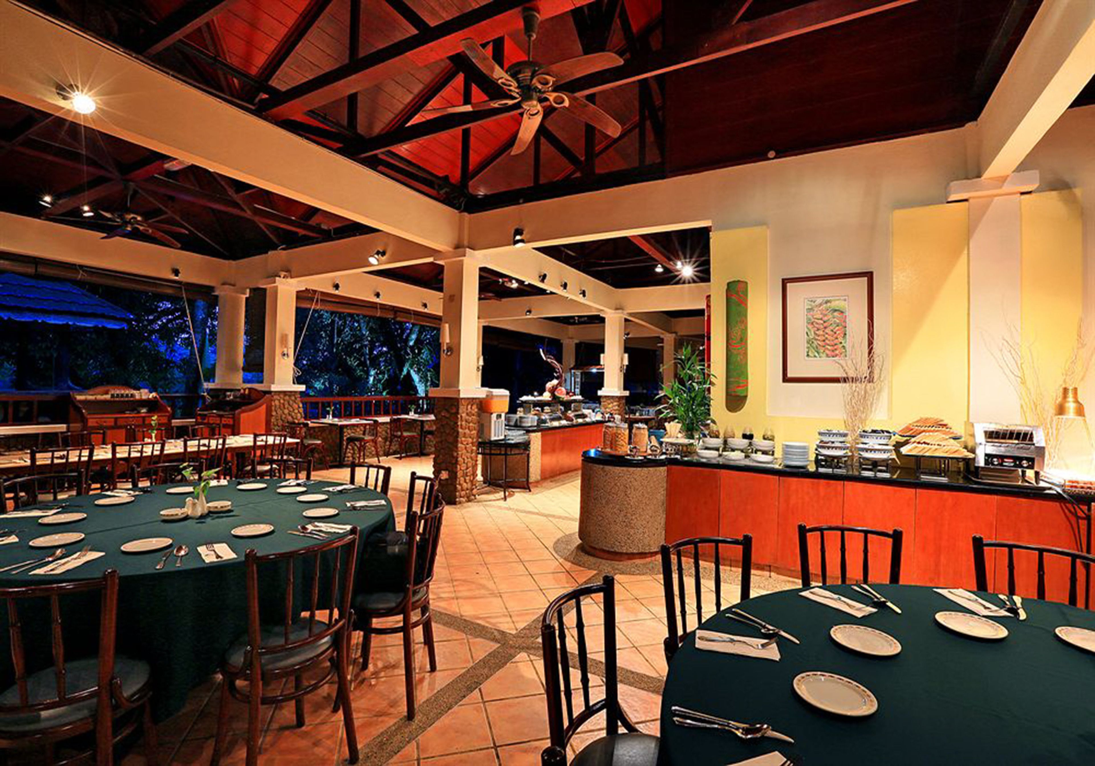 Een restaurant met meerdere tafels voor diners, een bar en uitzicht op het omliggende landschap.