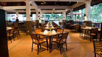 A restaurant with multiple dining tables and chairs, a tiled floor, and a view of the outdoors.