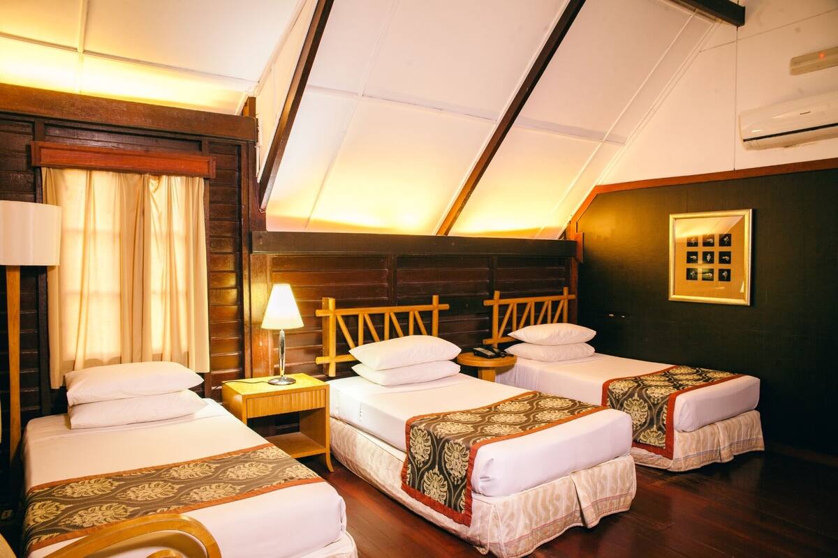 Een hotelkamer met twee enkele bedden, een houten hoofdbord, een nachtkastje met een lamp en een lijst met een foto aan de muur.