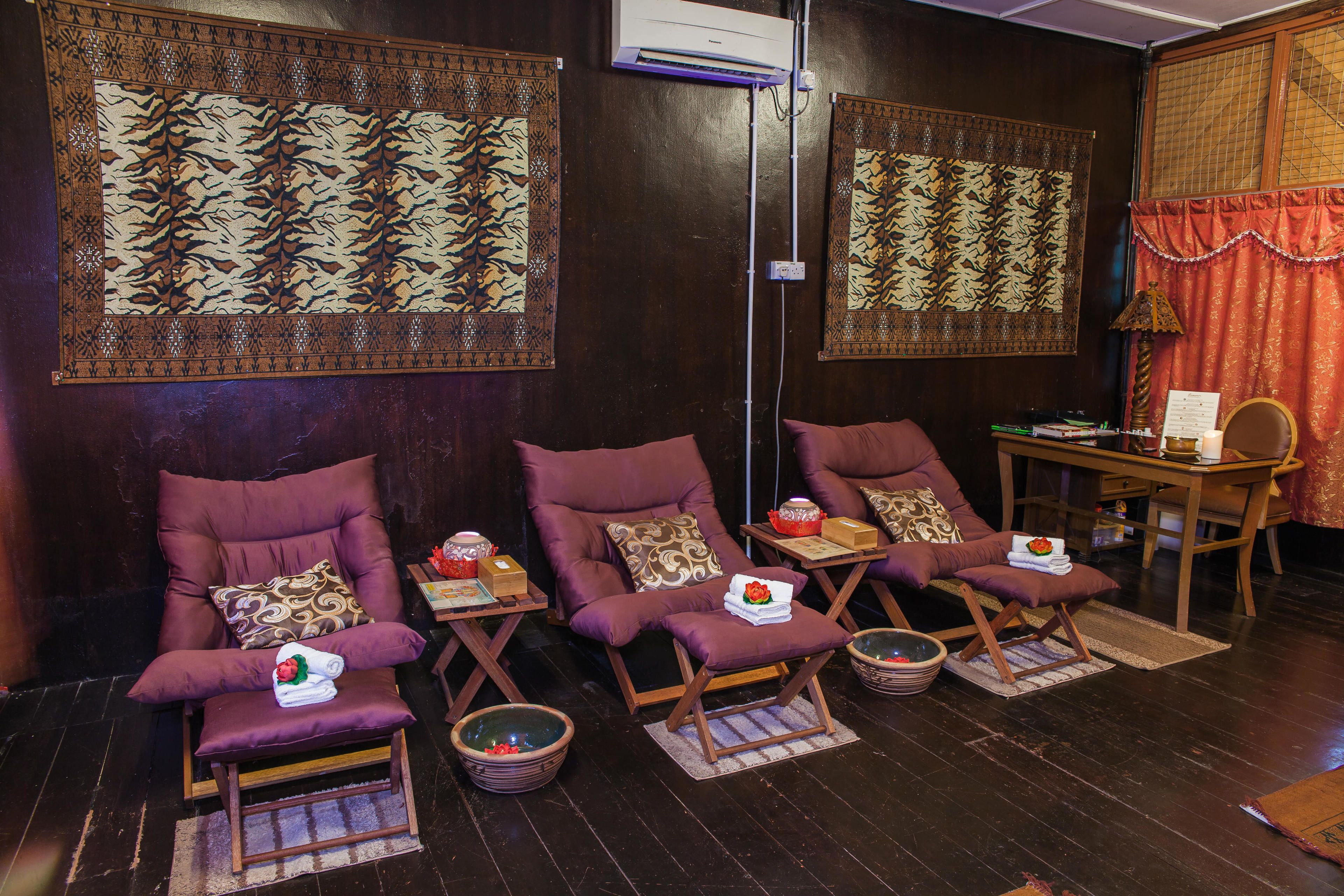 A room with three purple chairs, each with a small table and a bowl. There are patterned wall hangings above the chairs.