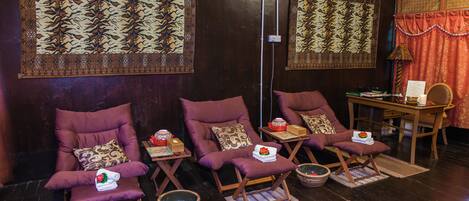 A room with three purple chairs, each with a small table and a bowl. There are patterned wall hangings above the chairs.