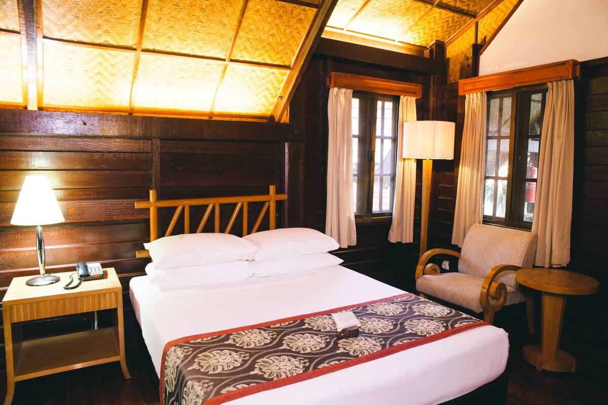 Een kamer met een bed, een stoel, een tafeltje en een lamp.