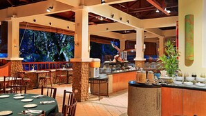Un restaurante con un pilar de piedra, una barra de buffet y un ventanal con vistas a árboles.