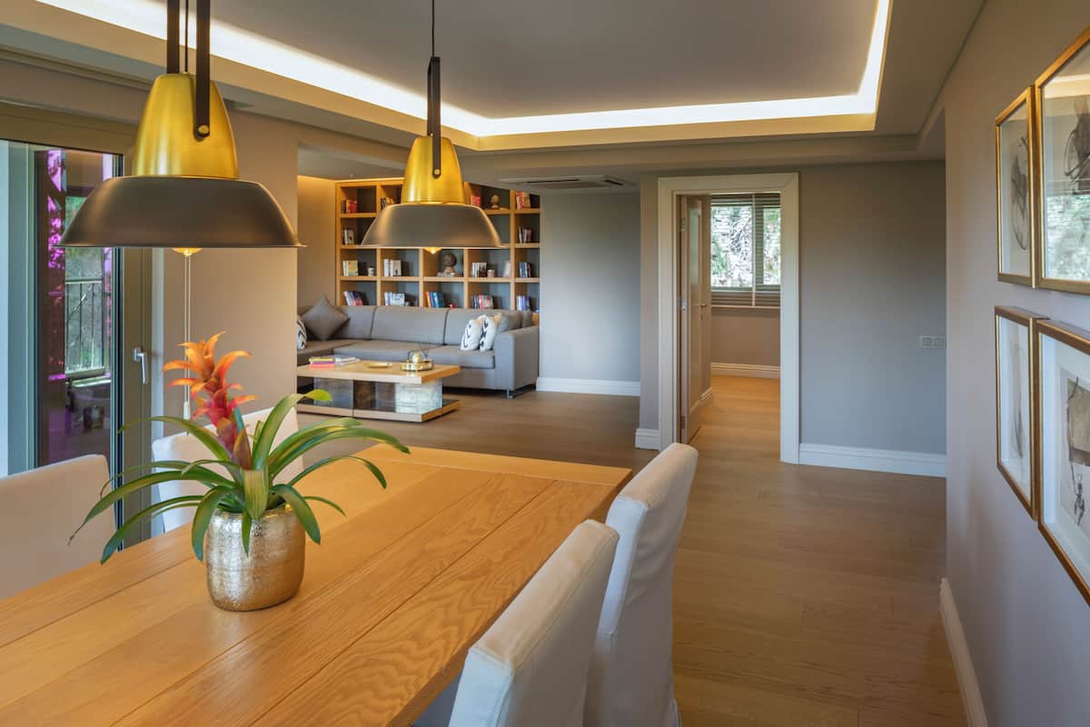 A modern living room with a wooden dining table, a sofa, and a bookshelf.