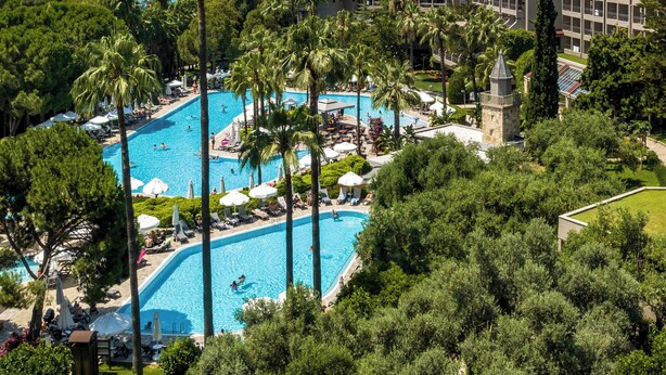 Un complexe hôtelier doté de plusieurs piscines, entouré de palmiers et offrant une vue sur l’océan.