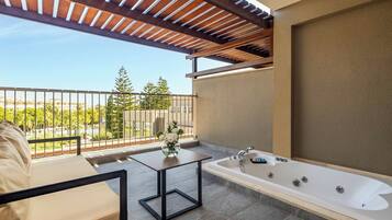 A balcony with a sofa, a small table with a vase, and a bathtub.