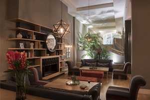 Una sala de estar moderna con chimenea, asientos cómodos y una planta grande.