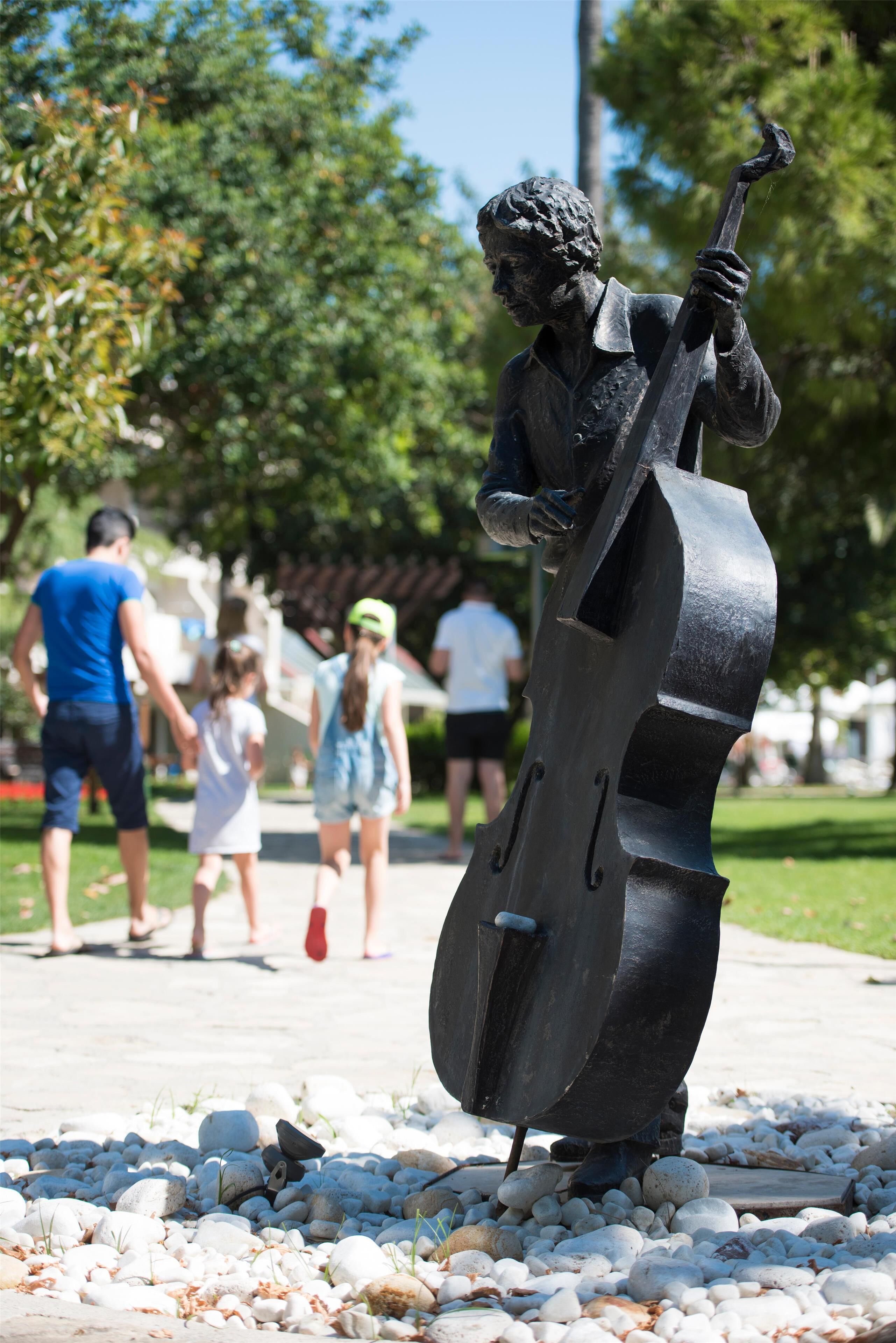 Una estatua de una persona tocando un contrabajo en un parque.