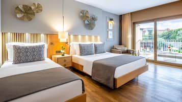 A hotel room with two beds, a balcony with a view, and decorative wall art.