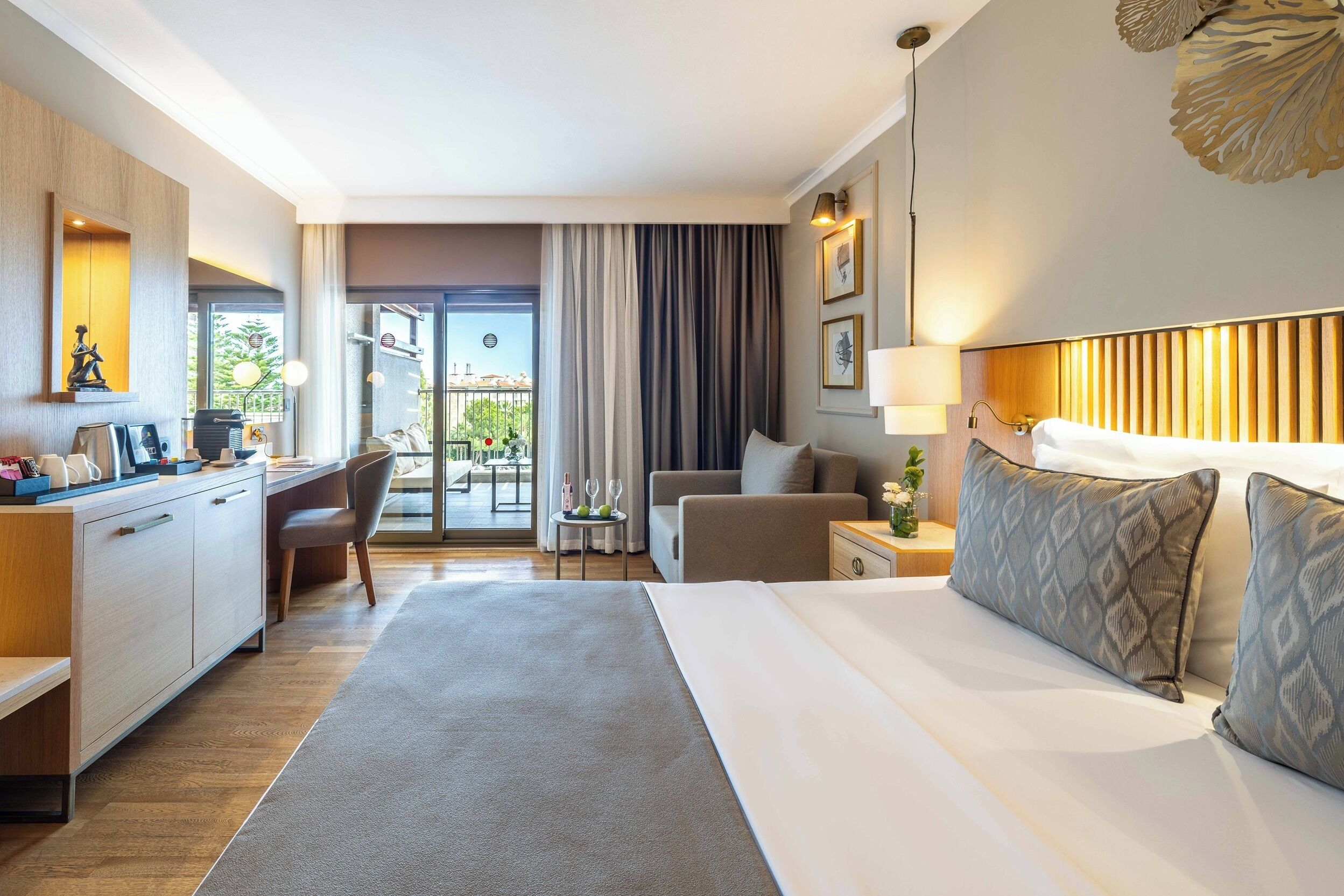 A hotel room with a bed, desk, chair, and a view of the outdoors.
