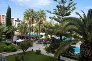Patio de un resort con mobiliario exterior, piscina y palmeras.