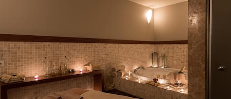 A hotel bathroom with a bathtub, a sink, and a shower. There are towels and toiletries on the counter.