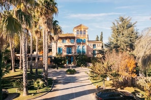 A large, multi-story building with a central courtyard, surrounded by palm trees and other vegetation.