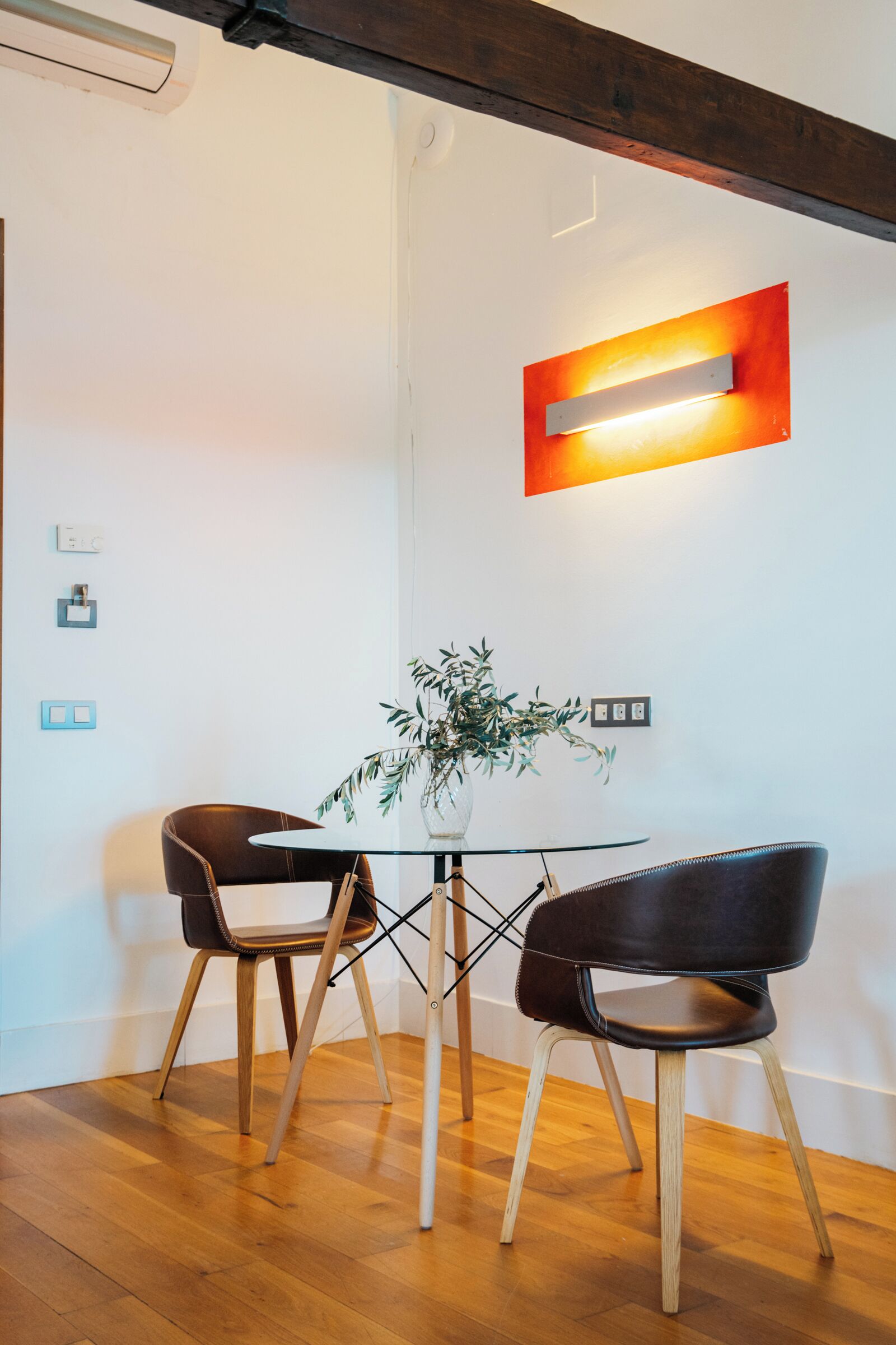 Un comedor moderno con dos sillones de cuero, una mesa de vidrio y una planta en maceta.