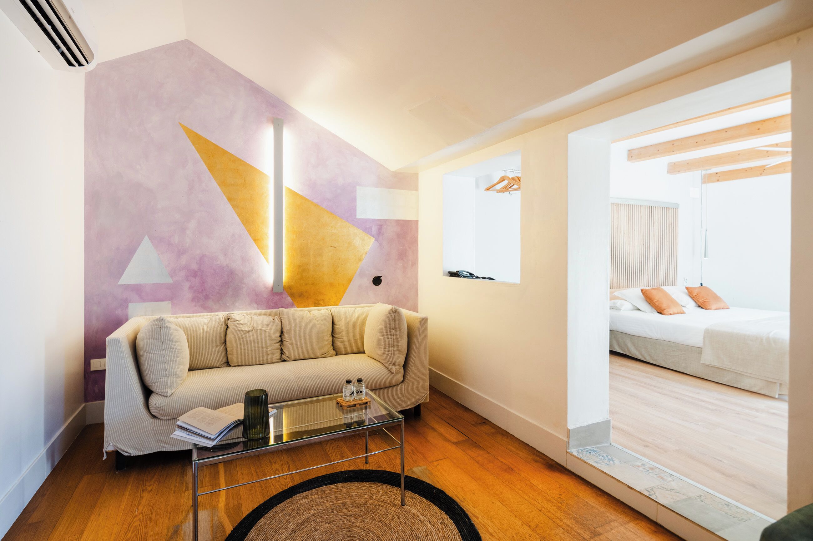 A modern living room with a sofa, coffee table, and a wall with geometric designs.