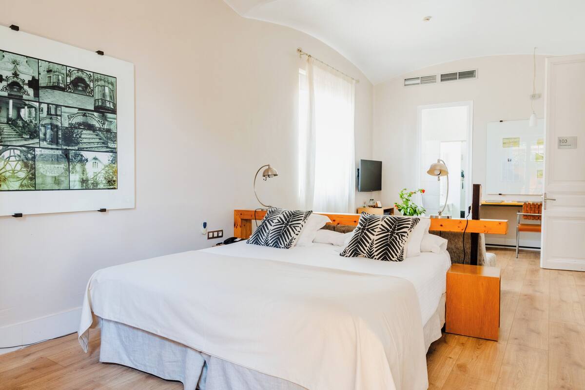 Quarto moderno com uma cama grande, uma escrivaninha, uma televisão e um quadro grande na parede.
