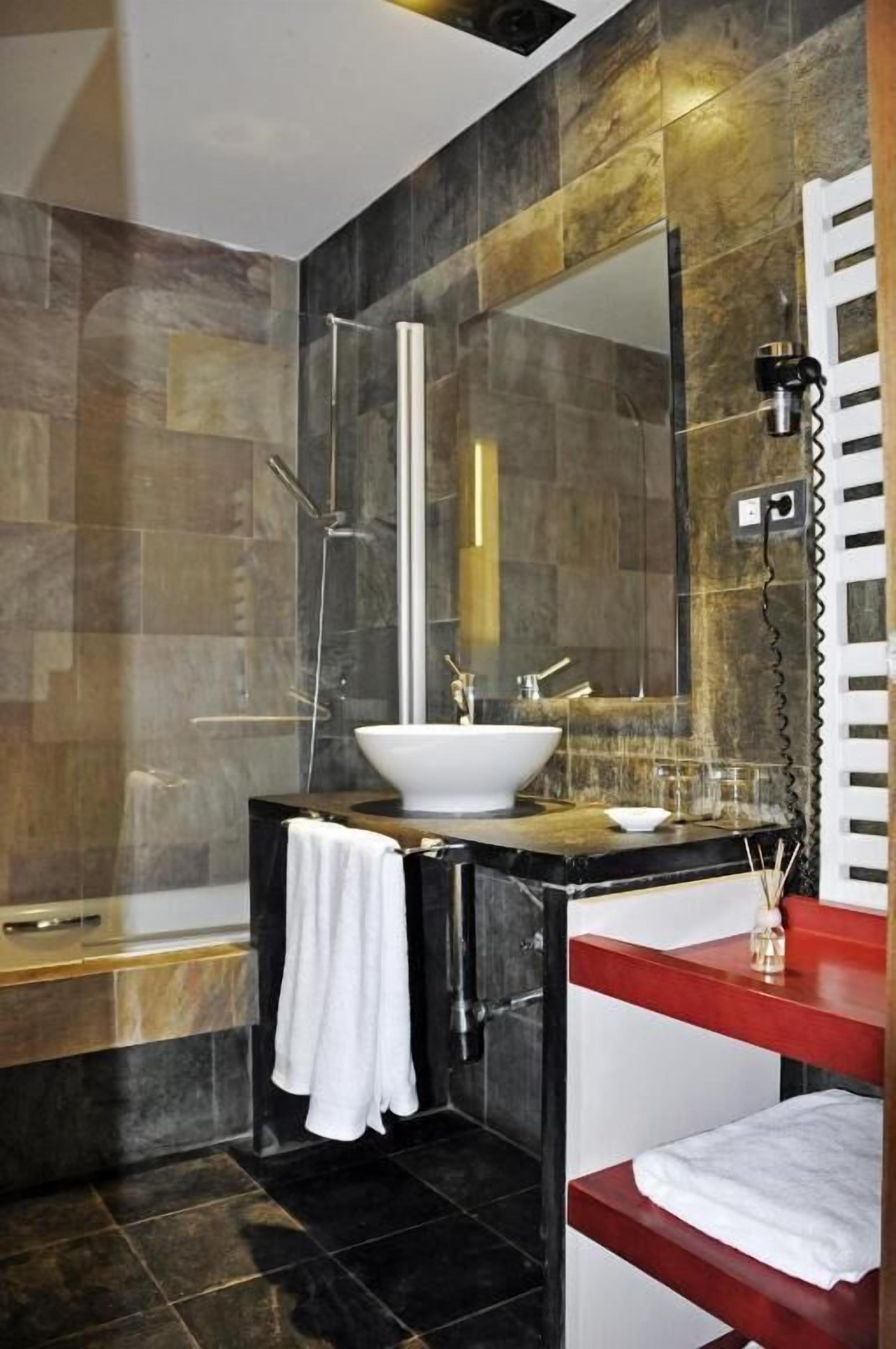 Une salle de bain moderne avec un grand miroir, un lavabo blanc et un espace douche.