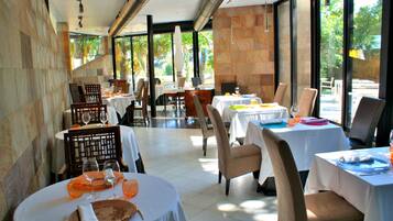 Un restaurante con varias mesas, sillas y vistas al exterior.